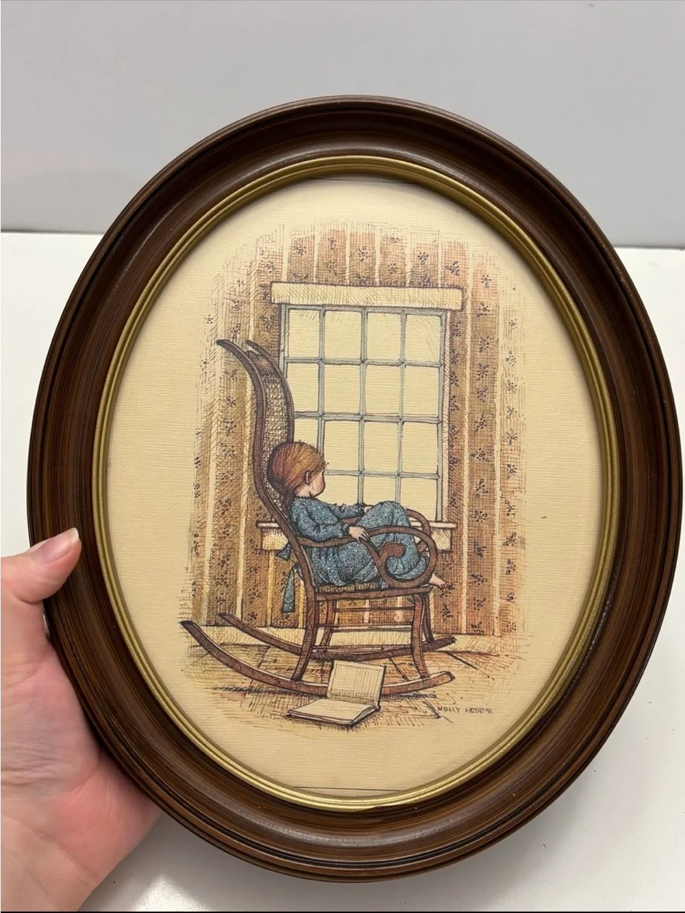 Vintage oval framed wall art piece featuring a girl in a rocking chair by a wind